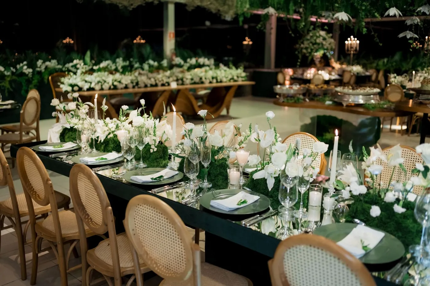 A long banquet table dressed with white flowers and candles
